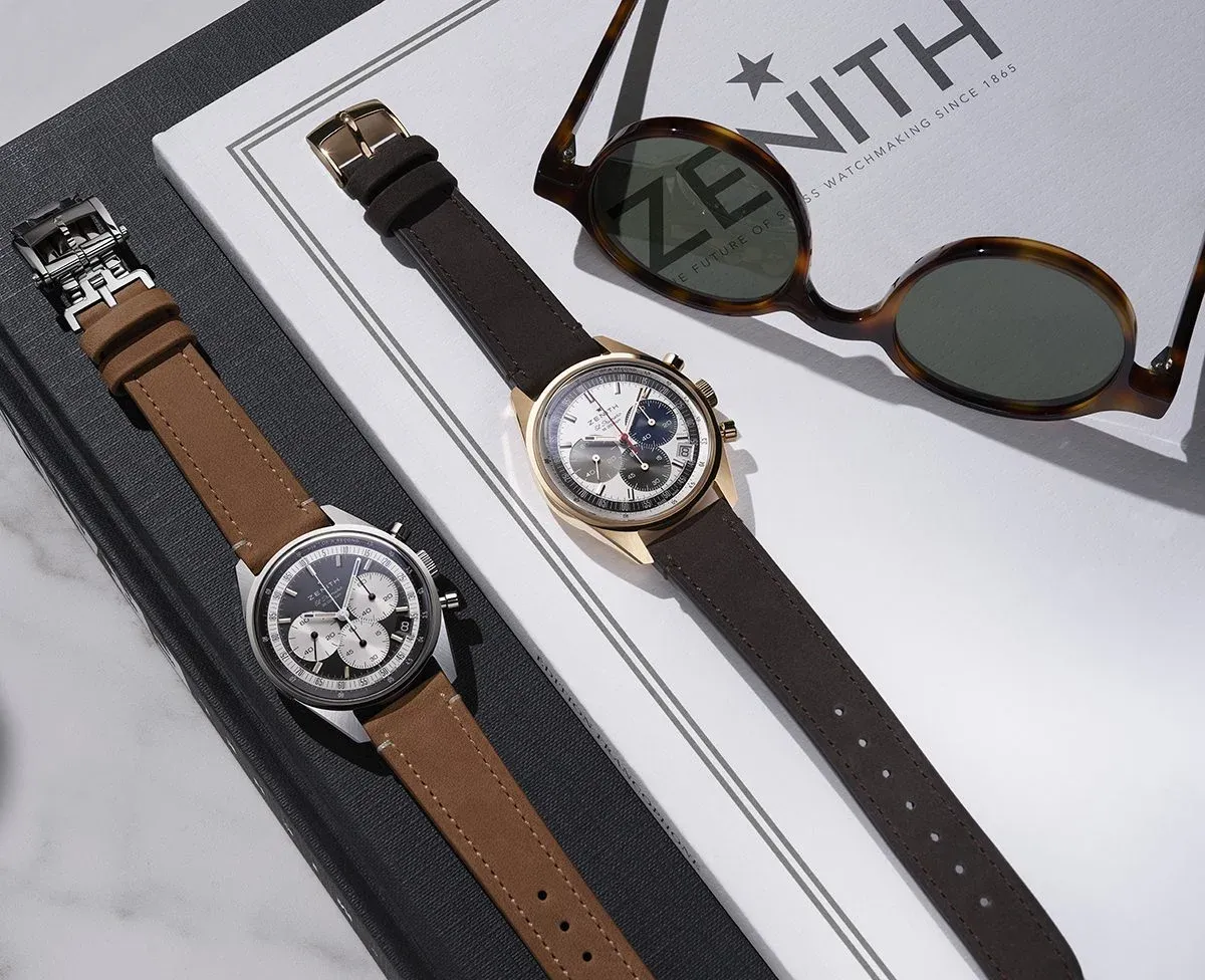 Two Zenith Chronomaster Original watches with brown and black leather straps, styled alongside sunglasses and branding.