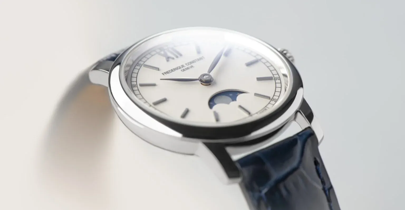 A white Frederique Constant watch featuring a blue leather strap, elegantly displayed on a pristine white surface