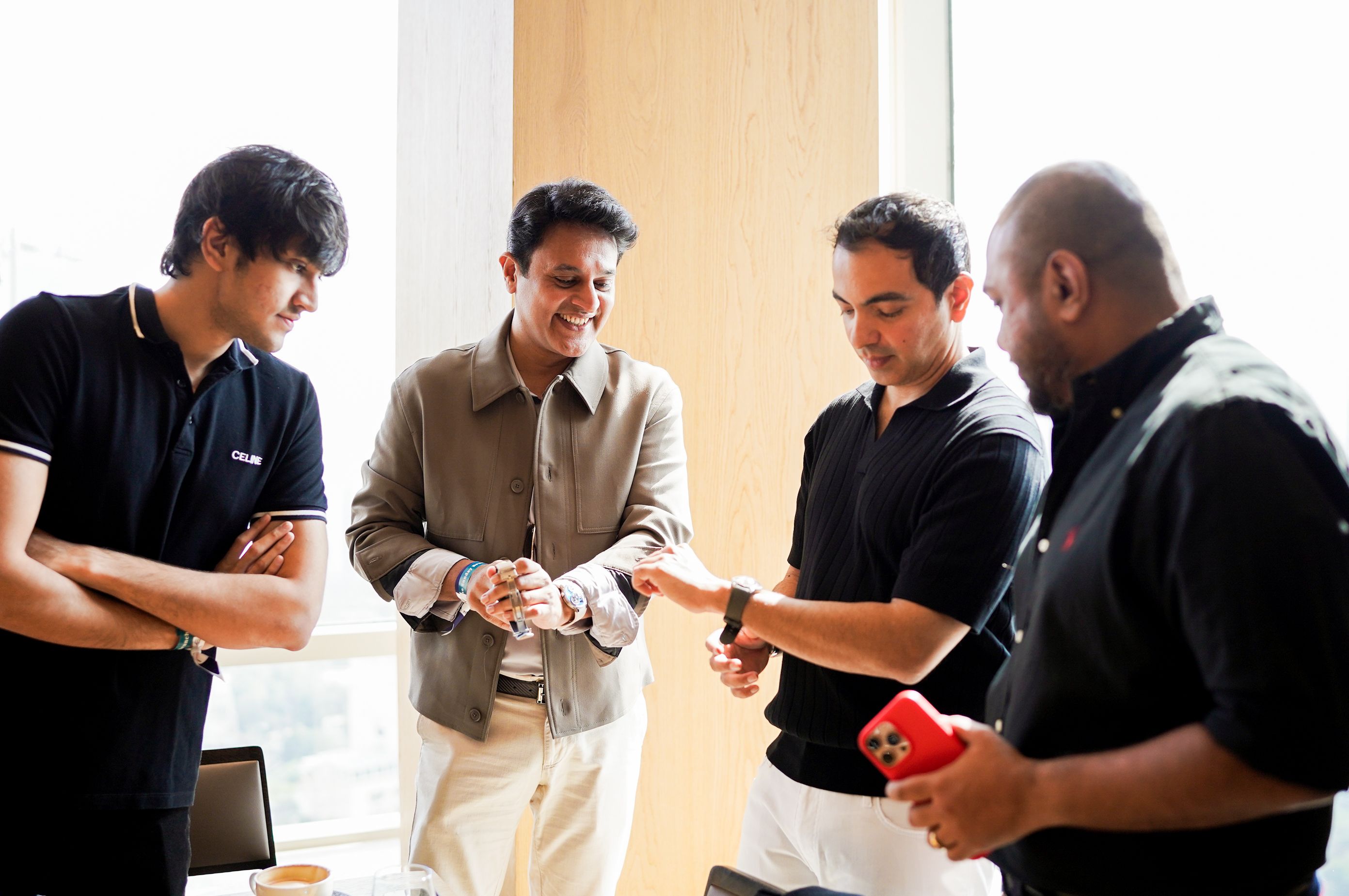 Watch collectors examining luxury timepieces during a horology meet featuring Rolex and Omega watches