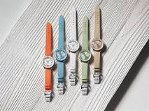 A collection of four elegant watches displayed on a pristine white surface, showcasing their unique designs and styles.