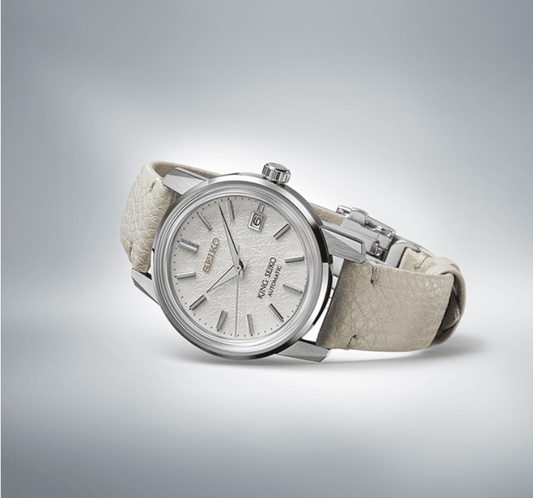 The watch is offered with an additional grey leather strap whose color and texture complement the patterned dial.